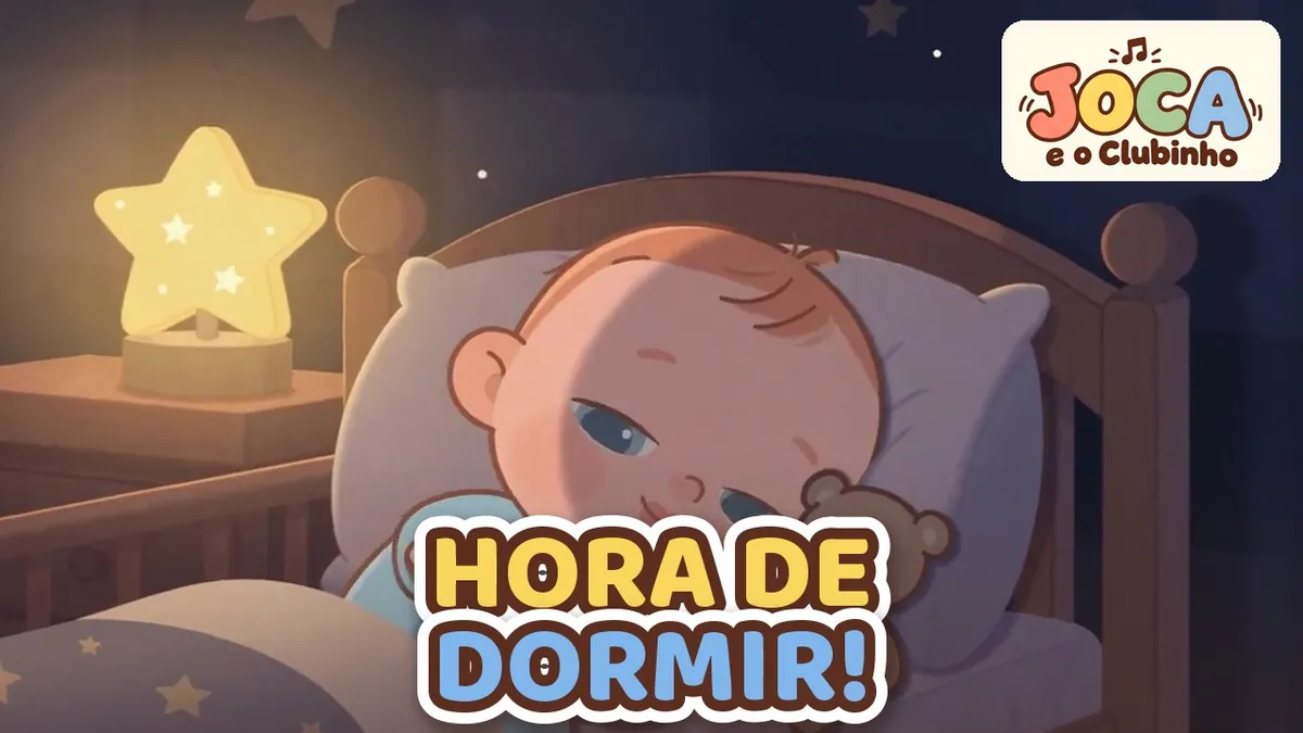 Joca dorme no berço de madeira abraçado ao ursinho, iluminado por uma luminária em forma de estrela, no clipe O Sono É um Presente